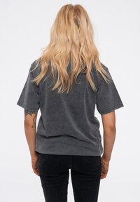 Dark gray cotton t-shirt with a relaxed fit and short sleeves, featuring a soft, textured surface. Back view shows shoulder seams and a round neckline.