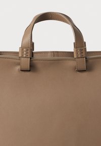 Bolso tote de cuero marrón con dos asas cortas, textura suave y sutiles acentos de costura en los bordes para mayor durabilidad.