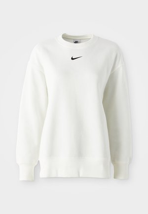 Bela majica s crewneck izrezom, izdelana iz mehkega bombaža, z spuščenimi rameni in črnim Nike logotipom na sredini prsnega dela. Splošni robovi in manšete.