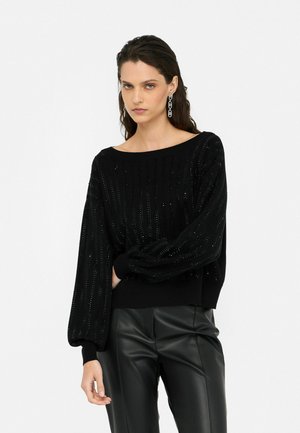 Maglione nero a maglia con righe verticali e dettagli scintillanti, scollatura a barca ampia e maniche a palloncino, abbinato a pantaloni in ecopelle neri.