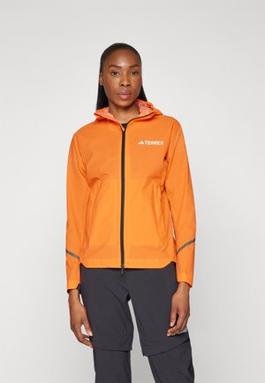 Veste imperméable orange avec fermeture éclair sur le devant, capuche ajustable et détails réfléchissants. Le matériau semble léger et respirant.