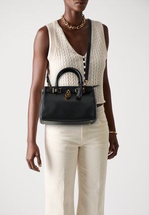 Black leather handbag with textured finish, dual top handles, long removable strap, gold hardware accents, and a decorative padlock detail.