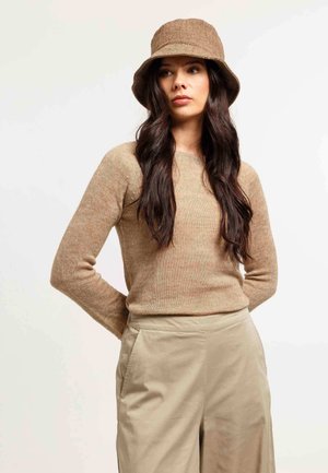 Gebreide trui in lichtbruin met een ronde halslijn, gecombineerd met beige wijde broek en een bijpassende textuur bucket hat.