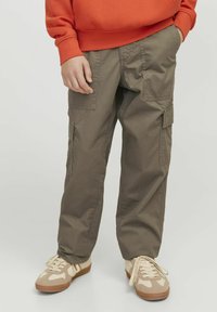 Cargo byxor i olivgrön bomullsmix, med flera sidfickor och en avslappnad passform, parat med beiga sneakers.