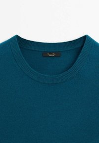 Pull col rond couleur sarcelle avec col en côte et étiquette en tissu noire cousue à l'intérieur du col.
