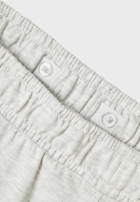 Ceinture élastique gris clair avec deux boutons blancs et texture froncée. Tissu doux et flexible avec un motif rayé subtil.