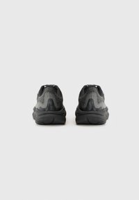 Des chaussures de sport noires avec une tige en mesh texturé, des semelles en caoutchouc épaisses et une forme arrondie. Présente un motif subtil le long des côtés.
