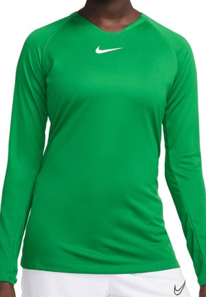 Grøn sportsbluse med lange ærmer og hvid Nike-logo på brystet båret af en delvist synlig person, kombineret med hvide bukser med sort Nike-logo.