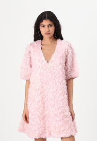 Roze jurk met een V-hals, korte pofmouwen en gelaagde rozen-applicaties. Zacht materiaal en uitlopende silhouette.