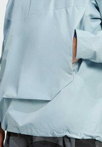 Jasnoniebieska, wodoodporna kurtka o luźnym kroju. Posiada dużą boczną kieszeń oraz elastyczne mankiety. Gładka tekstura i minimalistyczny design.