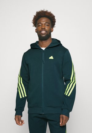 Donkergroene zip-up hoodie van zacht materiaal met een ruime capuchon. Heeft neon groene accentstroken op de mouwen en een klein logo op de borst.
