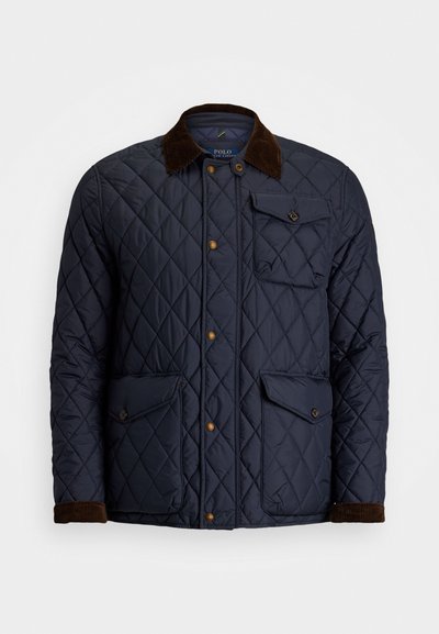 Jūras zils quiltots sporta mētelis ar brūnu korduroja apkakli, snap pogām, četriem priekšējiem kabatām un ribinātām piedurknēm. Iekļauj dimanta rakstu dizainu.