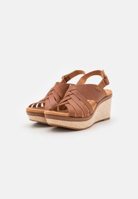 Sandales compensées en cuir marron avec un design supérieur tissé, bout ouvert et plateforme à motifs. Bride ajustable au talon pour un bon maintien.