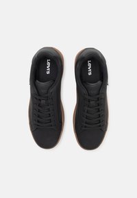 Schwarze Sneakers mit glatter Textur, Schnürdesign und braunen Gummisohlen. Mit einem "Levi's"-Logo auf der Zunge und der Seite.