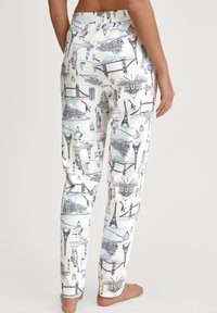 Witte, zachte stoffen broek met een multikleurige print van iconische bezienswaardigheden, waaronder de Eiffeltoren en de Londen Bridge.