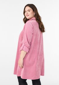 Roosa respo dress, millel on krae, pikad varrukad, mis on üles keeratud, ja laokas lõige, pehme tekstuur ja põlvepikkune ääre.