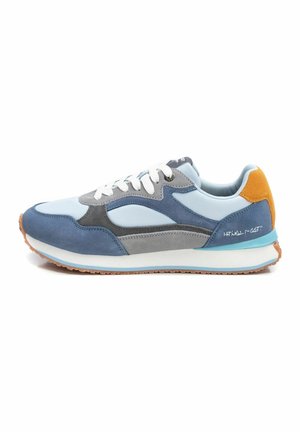 Zapatilla con una mezcla de gamuza azul claro y gris, cordones blancos y un acento en el talón de color naranja. Presenta una mediasuela acolchada y una suela texturizada.