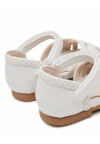 Sandali bianchi in pelle con dettagli intrecciati e cinturini regolabili; dotati di una piccola suola in sughero per comfort e durata.