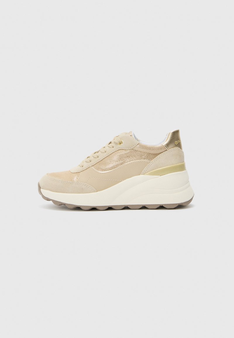 Beige sneakers med semsket skinn og teksturert stoff, med en tykk hvit mellomsåle og gullfarget detaljer på hælen og sidene.