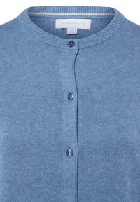 Cardigan bleu clair en tissu tricoté doux. Il présente un col rond, une fermeture à boutons et des poignets côtelés. L'étiquette indique "brookshire", taille S.