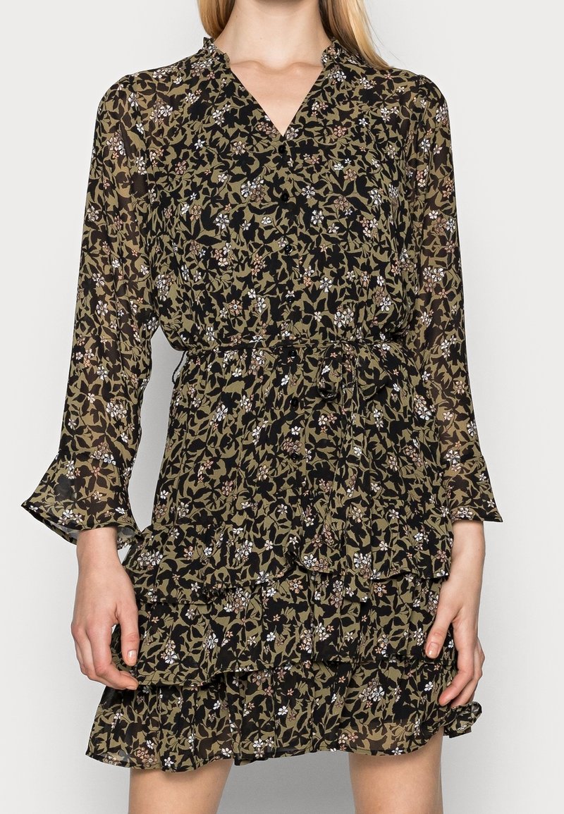 Robe à manches longues vert olive et noir à motif floral, avec volants à plusieurs niveaux, encolure en V et taille cintrée.