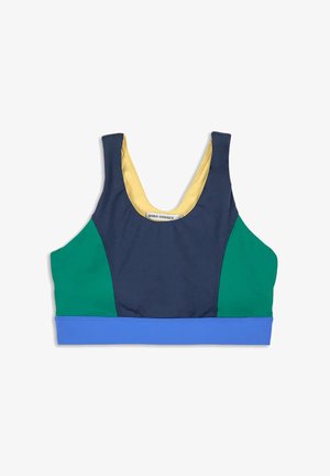 Bra sportivo color block con davanti blu navy, pannelli laterali verdi, banda inferiore blu e fodera interna gialla, posato orizzontale su sfondo bianco.