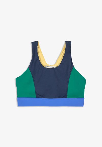 Färgbockad sport-bh med marinblå framdel, gröna sidopaneler, blå nederkant och gul innervadd, liggande platt på vit bakgrund.