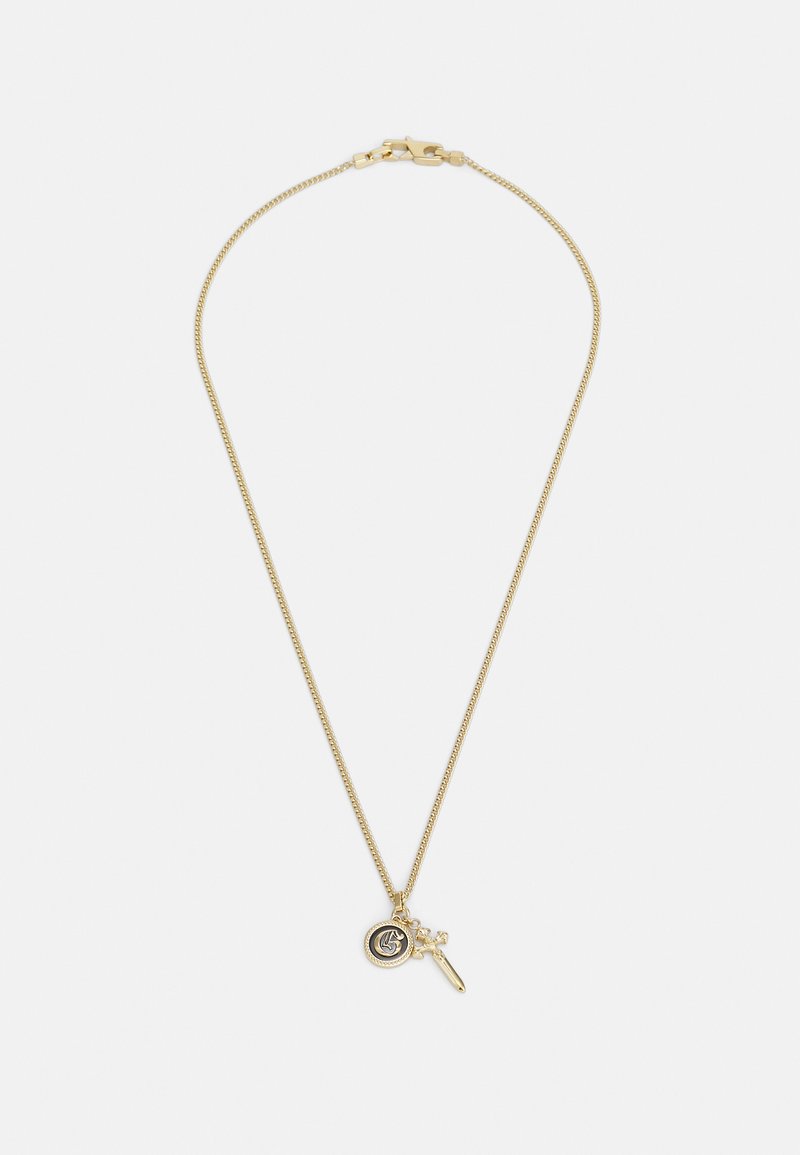 Collier en ton or avec une fine chaîne. Il présente un charm rond avec un détail de logo et un petit pendentif avec une touche. Les deux sont délicatement fabriqués.