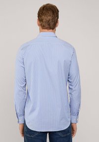 Camicia a maniche lunghe a righe blu e bianche con colletto, bottoni ai polsini e orlo curvo, realizzata in un tessuto leggero.