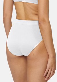 Slip bianchi a vita alta con una texture liscia, design senza cuciture e cuciture minime. Tessuto morbido per comfort e vestibilità.