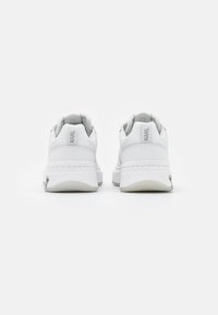 Białe trampki z gładką skórzaną cholewką, zaokrąglonym noskiem i wyściełanym kołnierzem. Posiadają logo na pięcie oraz grubą białą podeszwę.