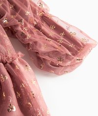 Różowa tkanina z tiulu o fakturowanym wykończeniu i wzorach z foliowym złotym kokardą. Zgromadzony, puszysty design z elastycznymi detalami na krawędziach.