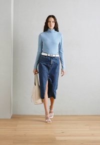Hele sinine pikkade käistega tops, mis on kombineeritud tumedast denimpallist, millel on ees tulebihk. Aksessuaarideks on valge vöö ja beež käekott.