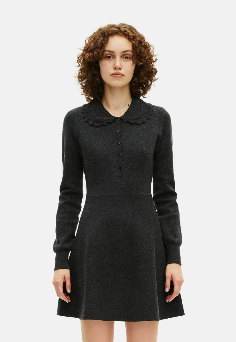 Abito maglione grigio scuro con colletto a scalloppature, maniche lunghe, apertura con bottoni e silhouette a gonna svasata. Realizzato in un morbido tessuto testurizzato.