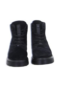 Pair of black suede lace-up boots with thick soles viewed from the front against a white background.