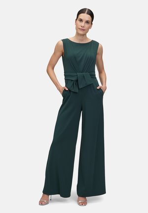 Dunkelgrüner Jumpsuit mit tailliertem Oberteil, einer Taillenschleife und weit geschnittenen Hosenbeinen. Hat einen runden Ausschnitt und Seitentaschen.
