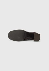 Scarpa di pelle marrone con punta quadrata e tacco basso e uniforme; texture liscia sulla tomaia e suola in gomma per una buona presa.