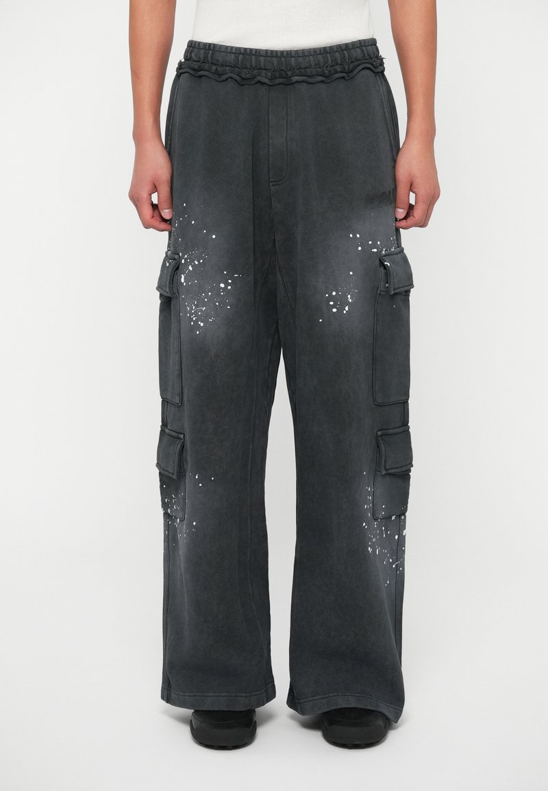 Cargo nohavice s voľným strihom, vyrobené z tmavosivej tkaniny, s množstvom vreciek a bielym rozstrapkaným vzorom. Elastický pás.