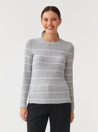 Harmaa pitkähihoinen paita, jossa on valkoisia vaakaraitoja, röyhelöinen pinta, pyöreä kaula-aukko ja slim fit -leikkaus, yhdistetty mustiin housuihin.