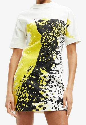Biała sukienka z krótkim rękawem z dużym czarno-żółtym nadrukiem przedstawiającym twarz i cętki lamparta z przodu.