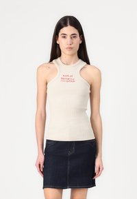 Beige geribbelde mouwloze top met een hoge nek en uitsnijdingen op de schouders, met in het rood gedrukt de tekst "REPLAY Monte Carlo Country Club."