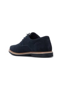 Zapatos de vestir de ante azul marino con punta redonda, diseño con cordones y suela en contraste en color marrón claro. Presentan una textura suave y detalles de costura sutiles.