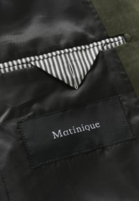 Černý textilní interiér s pruhovanou kapsou v bílé a černé barvě. Štítek s nápisem "Matinique" vyšitém bílou nití na černé nášivce.