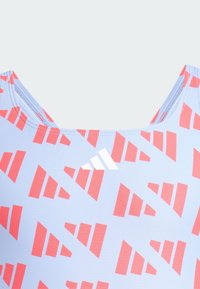 Maillot de bain en tissu bleu clair avec un motif géométrique rouge. Conçu avec un col rond et rehaussé d'un logo blanc.