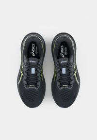 Zwarte hardloopschoenen met een bovenwerk van mesh, reflecterende accenten en heldergele logo's. Ontworpen voor comfort, met een gevoerde zool en veters.