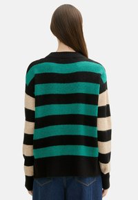 Gestreifter Pullover mit kräftigen Farben in Schwarz, Türkis und Beige. Weicher Stoff, runder Ausschnitt und Design mit überschnittenen Schultern.