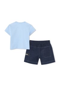 Lichtblauw T-shirt met korte mouwen, gecombineerd met donkere denimshorts. De shorts hebben twee achterzakken en een merklabel op de tailleband.