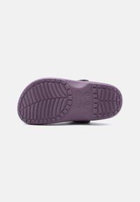 Chaussure Crocs violette vue du dessous, montrant le motif texturé de la semelle et les marquages de taille sur un fond blanc uni.