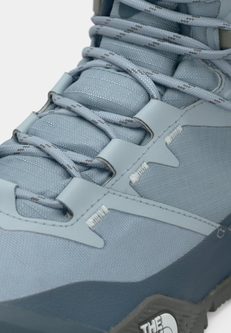 Lyseblå vandresko med tekstureret syntetisk overdel, forstærkede snørehuller, kontrastfuld mørkeblå sål og mærkeaccent på siden.