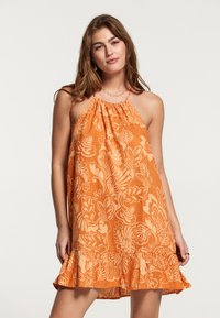 Vestido naranja con cuello halter, que presenta un patrón floral y un dobladillo con volantes. Tejido ligero con una textura suave.